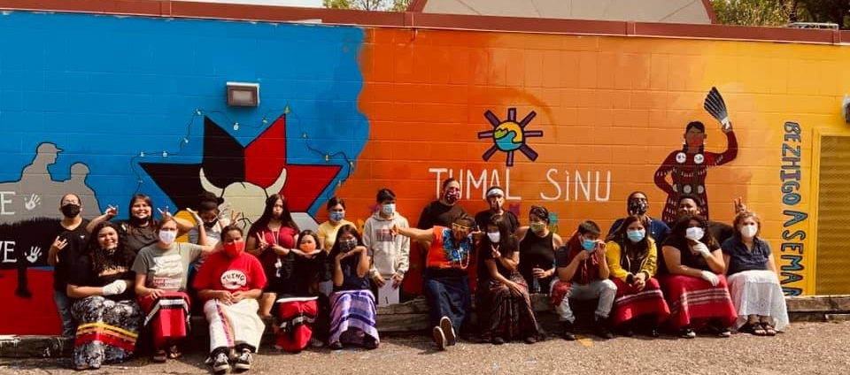 youth sitting in front of mural they painted.